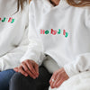 Red, Green, Aqua, and Pink embroidered letters "Holly Jolly" on white hoodies